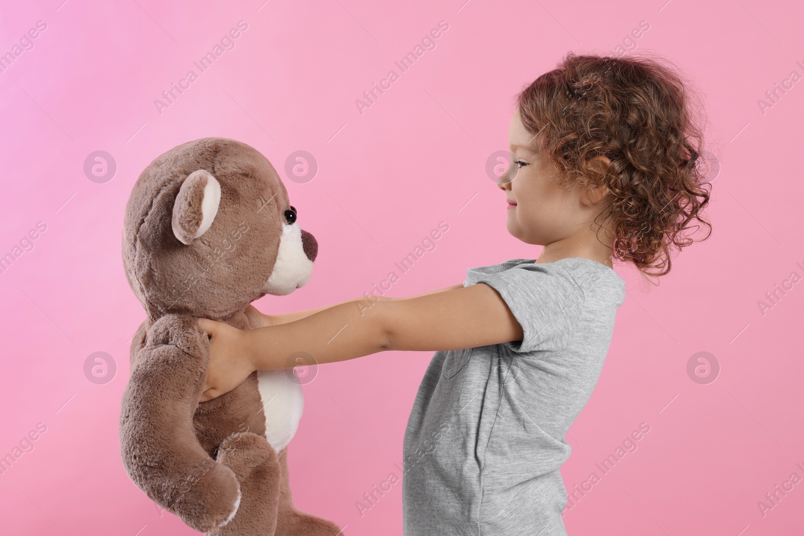 Photo of Cute little girl with teddy bear on pink background