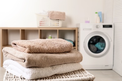 Stack of clean soft towels on basket in laundry room. Space for text