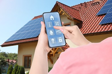 Woman using smart home control system via mobile phone near house outdoors, closeup