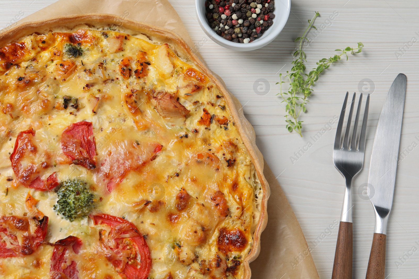 Photo of Tasty cheese quiche and cutlery on white wooden table, flat lay