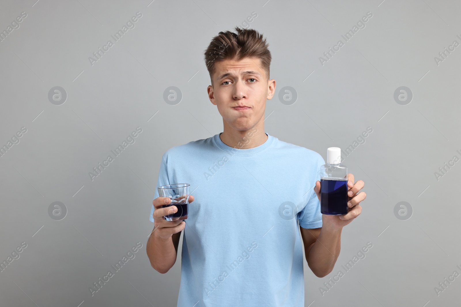 Photo of Young man using mouthwash on light grey background