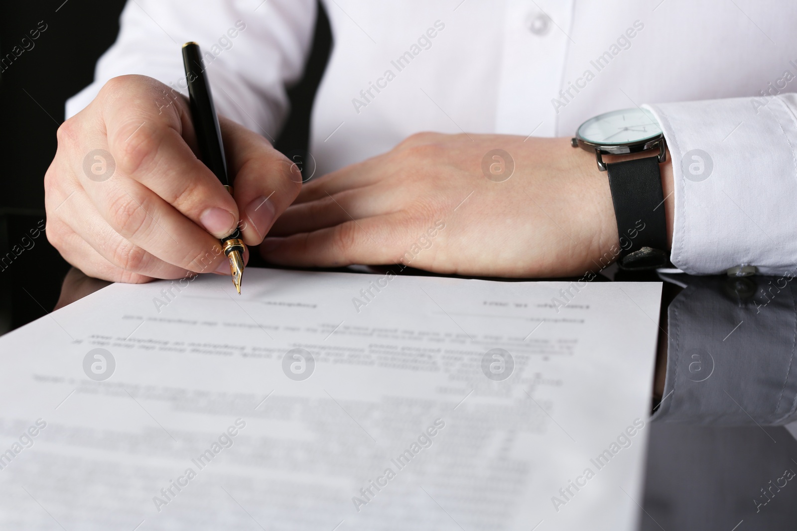 Photo of Notary signing document at black table, closeup