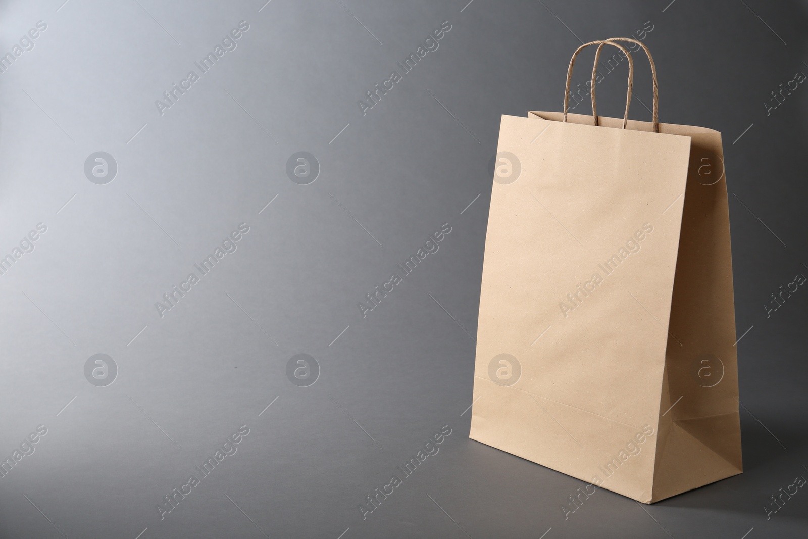 Photo of One kraft paper bag on grey background, space for text. Mockup for design