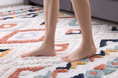 Photo of Woman walking on carpet with pattern at home, closeup