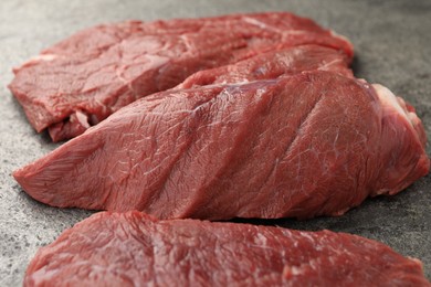 Pieces of raw beef meat on grey table, closeup