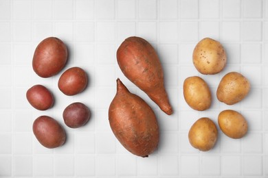 Different types of fresh potatoes on white table, flat lay