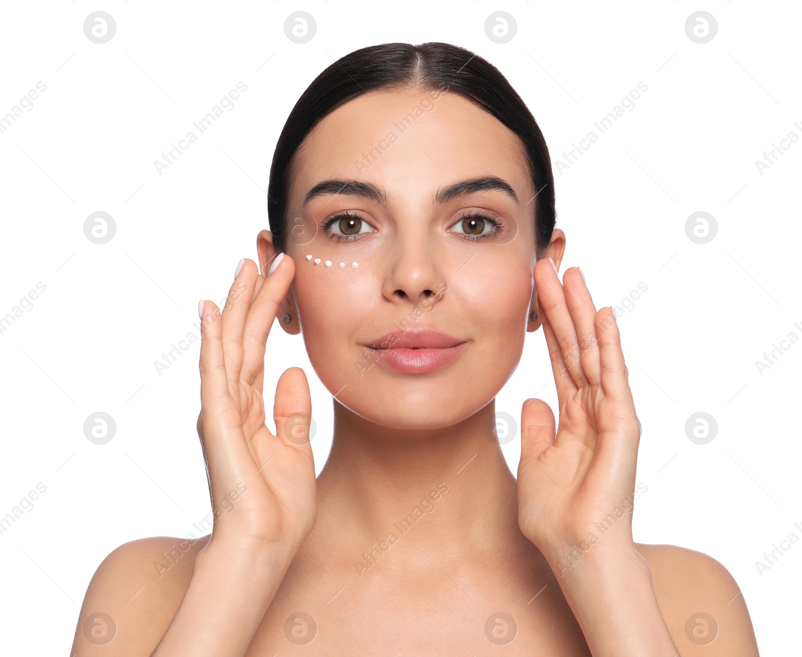 Photo of Beautiful young woman with cream on skin under eye against white background