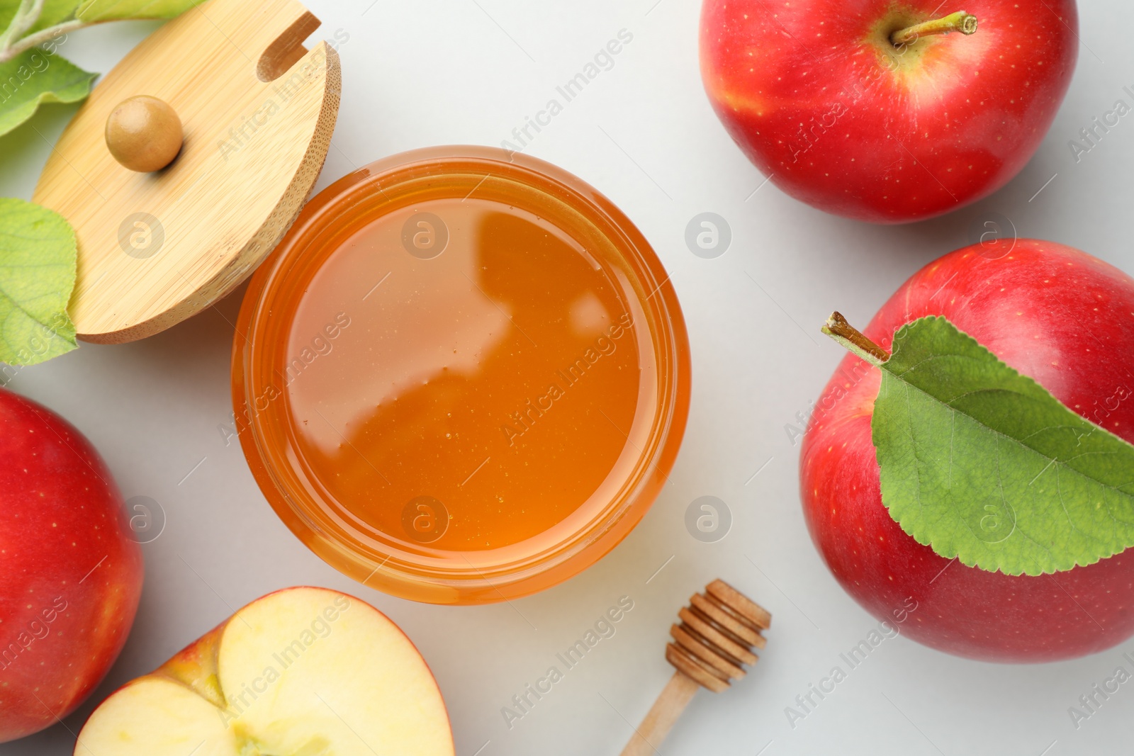 Photo of Sweet honey and fresh apples on white table, flat lay