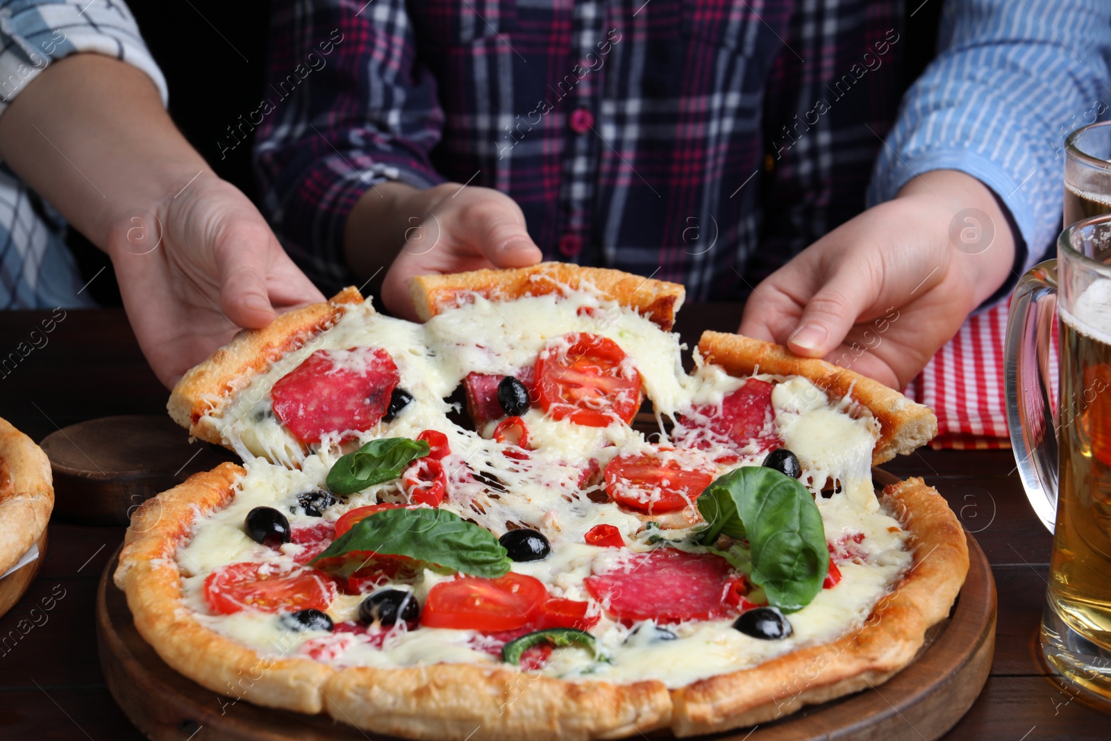 Photo of Friends taking pieces of delicious pizza Diablo at table, closeup