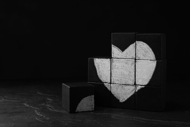 Photo of Heart drawn on black cubes. Composition symbolizing problems in relationship