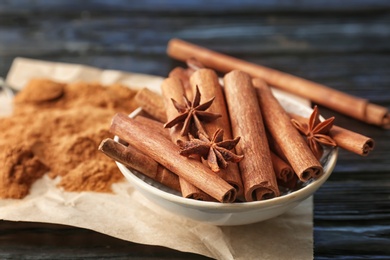 Photo of Bowl with aromatic cinnamon sticks and powder on table