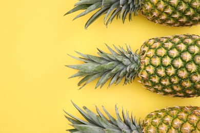Photo of Delicious ripe pineapples on yellow background, flat lay. Space for text