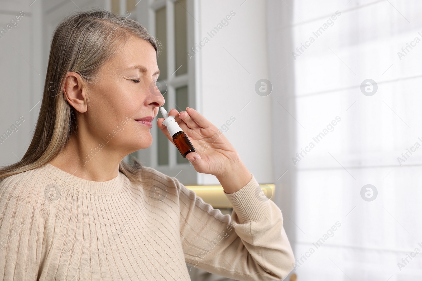Photo of Medical drops. Woman using nasal spray indoors, space for text