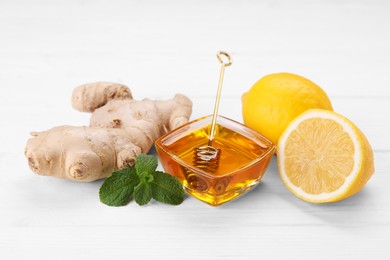 Natural cough remedies. Bowl with honey, ginger, mint and lemon on white table