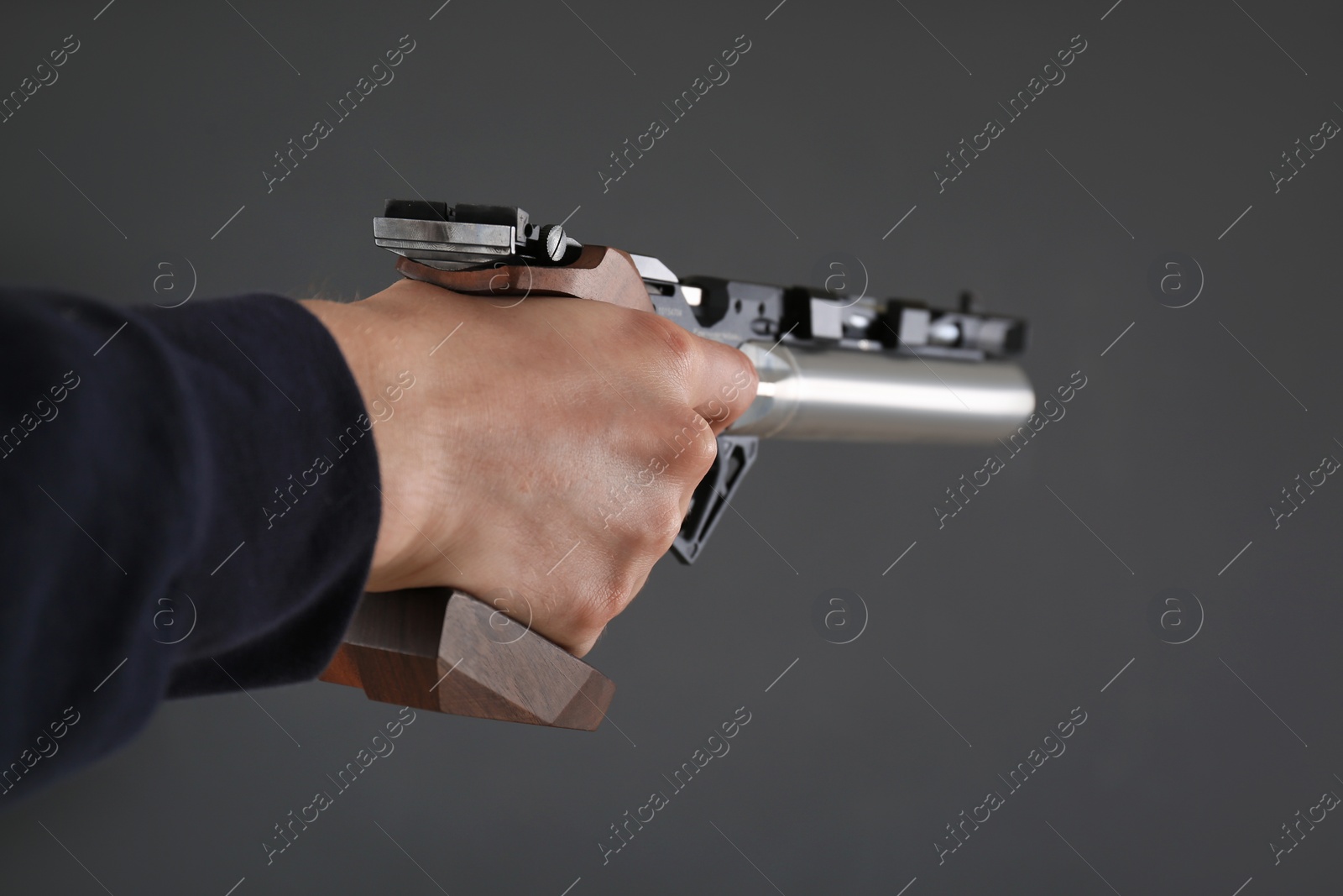 Photo of Gun shooting sport. Man aiming standard pistol on dark background, closeup