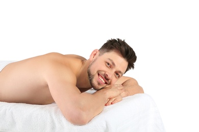 Handsome man relaxing on massage table against white background. Spa service