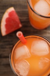 Photo of Tasty freshly made grapefruit juice and fruit on wooden table, top view