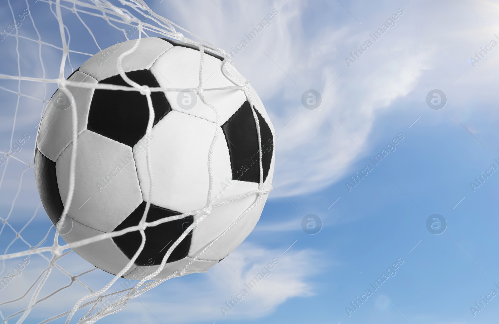 Image of Soccer ball in net against blue sky