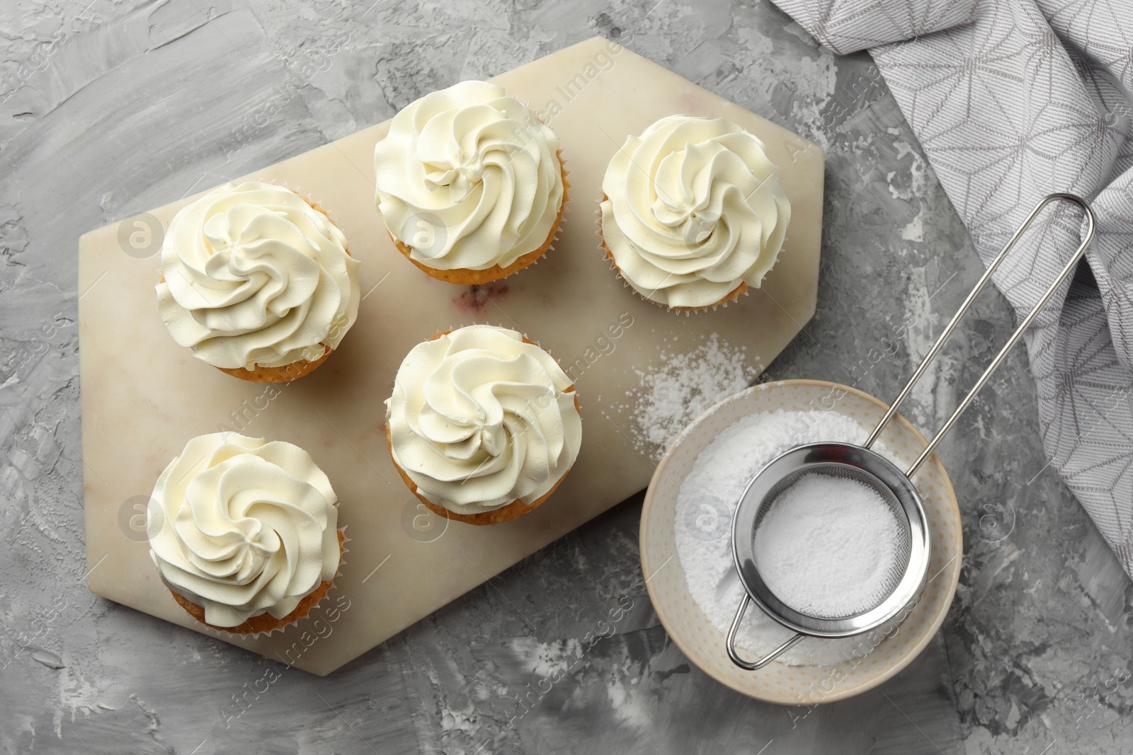 Photo of Tasty cupcakes with vanilla cream on grey table, top view