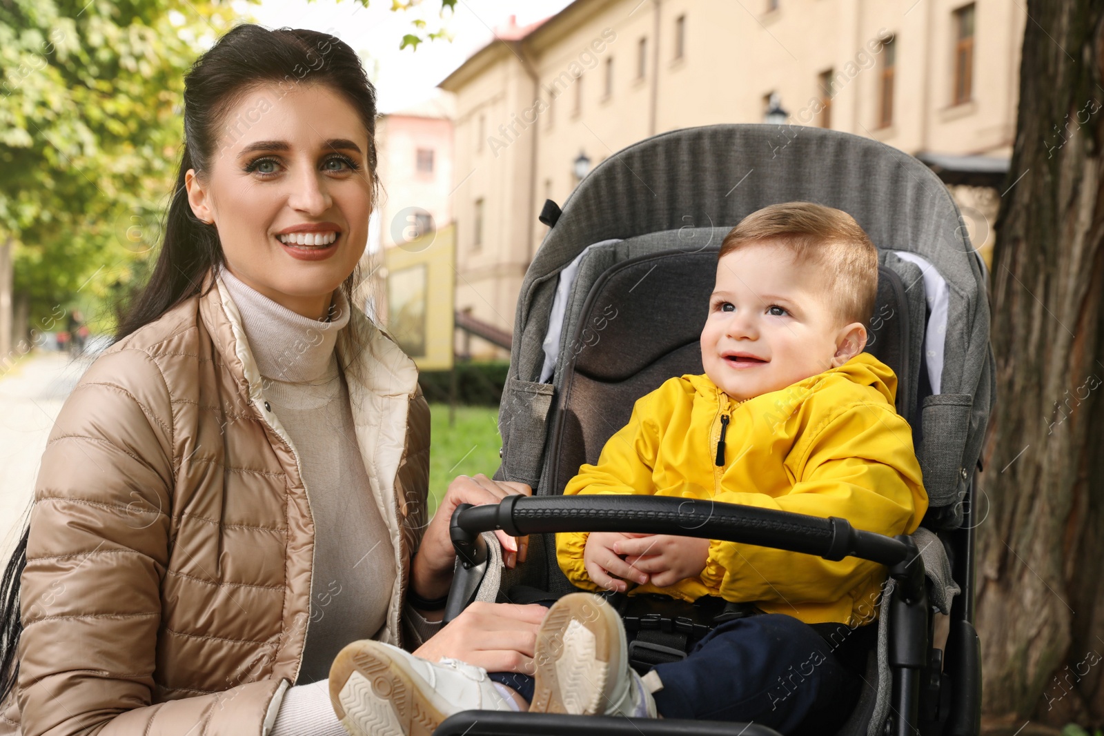 Photo of Happy mother with her son in stroller outdoors