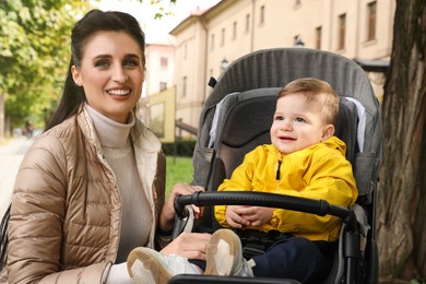 Happy mother with her son in stroller outdoors