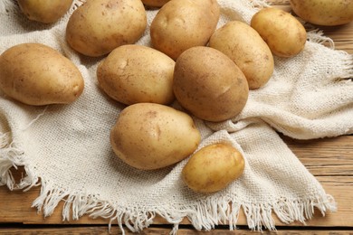 Photo of Raw fresh potatoes and napkin on wooden table