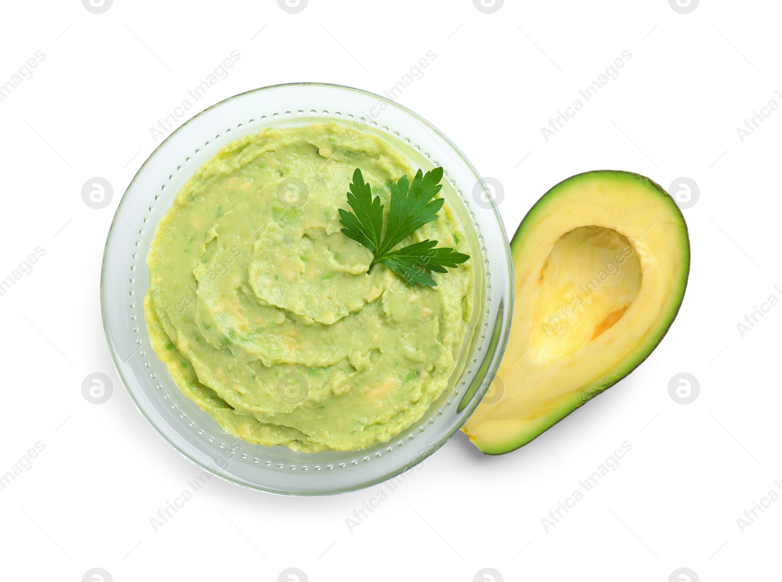 Photo of Glass bowl of tasty guacamole with parsley and cut avocado on white background, top view