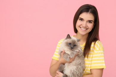 Photo of Happy woman hugging her cute cat on pink background, space for text