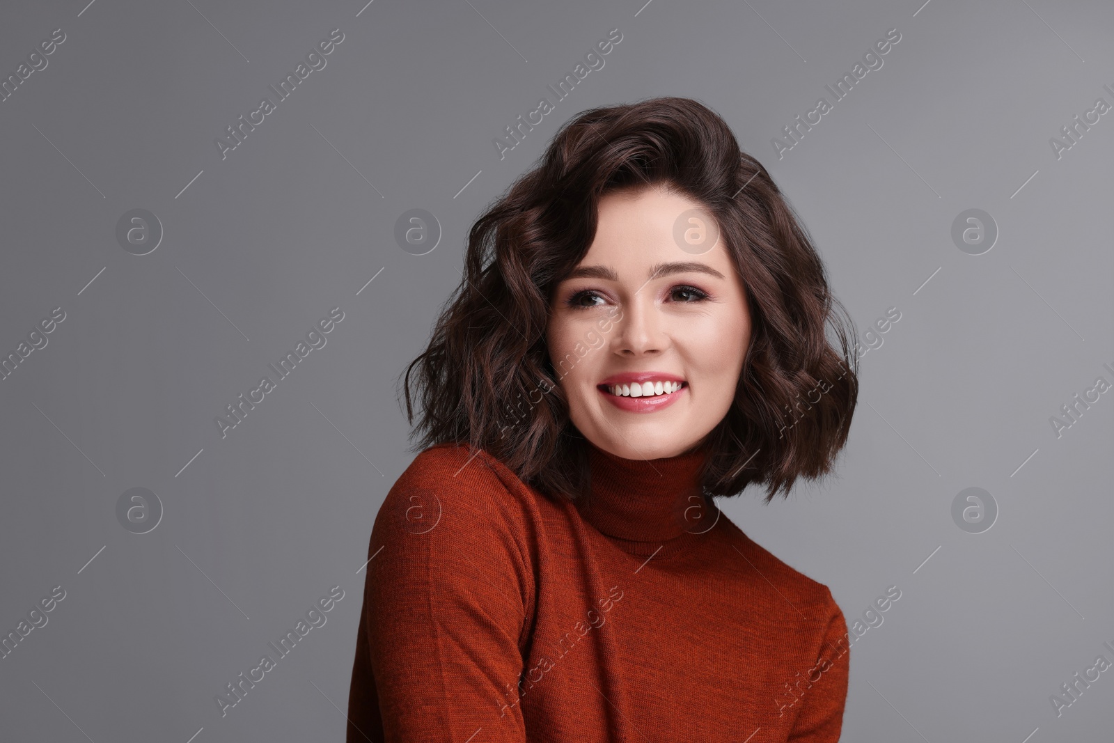 Photo of Portrait of beautiful young woman with wavy hairstyle on grey background. Space for text