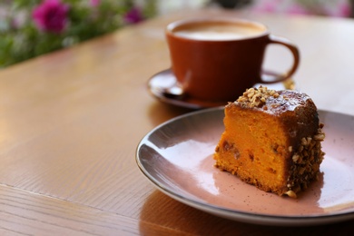 Plate with slice of carrot cake on wooden table