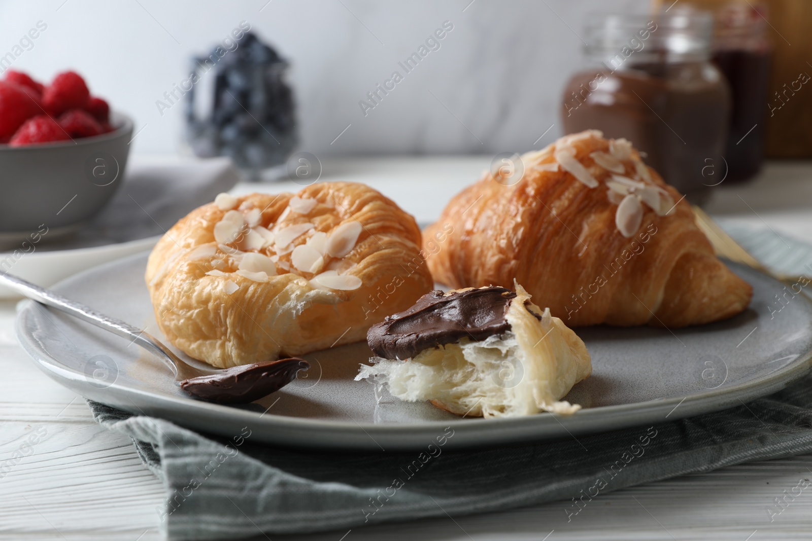 Photo of Delicious croissants with almond flakes and chocolate on table, closeup