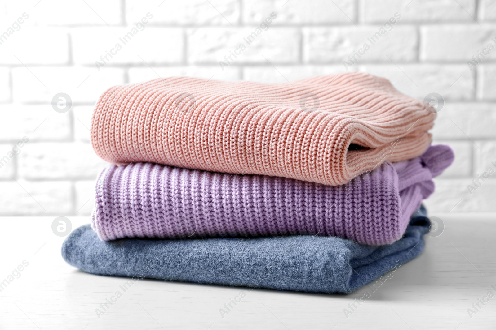 Photo of Stack of warm knitted clothes on table