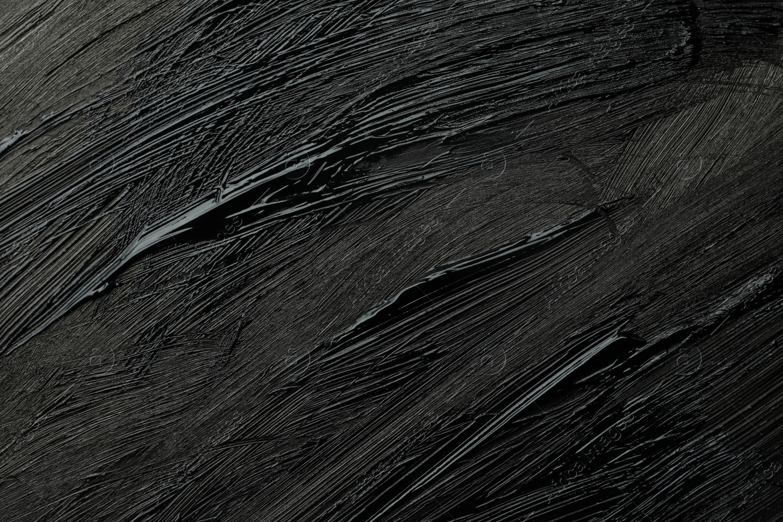 Photo of Beautiful strokes of black paint as background, closeup