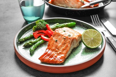 Photo of Plate with tasty cooked salmon on table, closeup