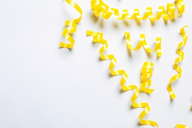 Photo of Yellow serpentine streamers on white background, top view