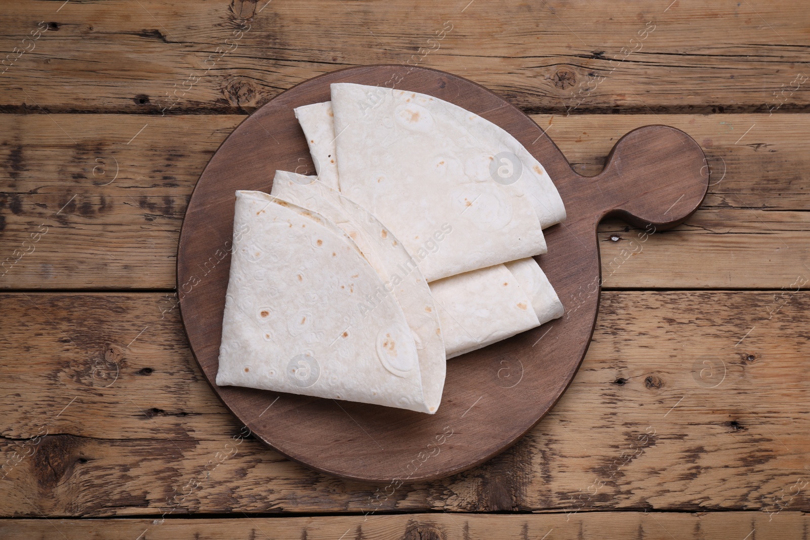 Photo of Delicious folded Armenian lavash on wooden table, top view