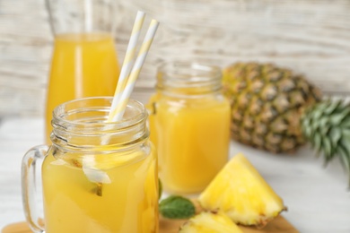 Photo of Mason jars with delicious pineapple juice on table