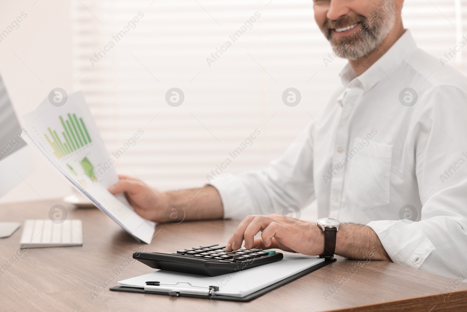 Photo of Professional accountant using calculator at wooden desk in office, closeup