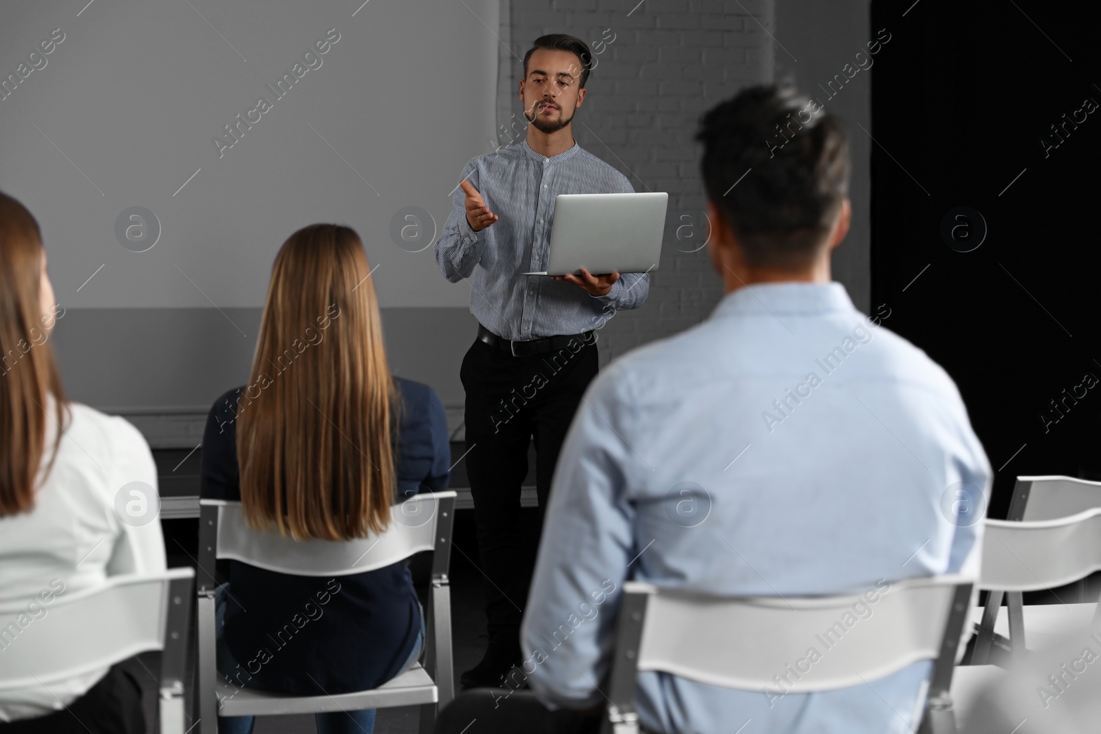 Photo of Male business trainer with laptop giving lecture in conference room with projection screen