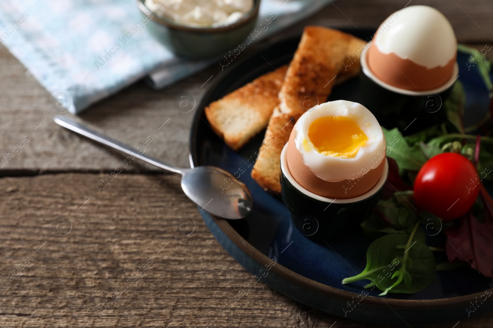 Photo of Delicious breakfast with soft boiled eggs served on wooden table, closeup