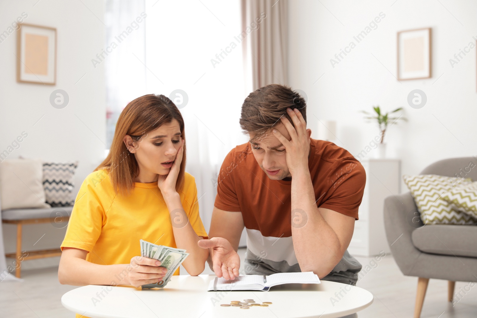 Photo of Sad couple counting money in living room