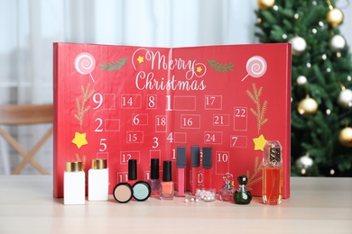 Photo of Christmas advent calendar with perfumes, skin care and decorative cosmetics on table