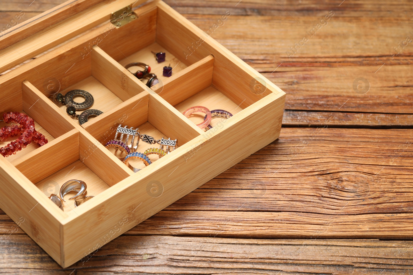 Photo of Jewelry box with many different accessories on wooden table. Space for text