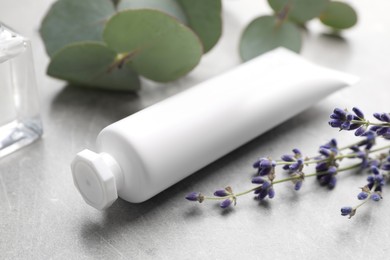 Photo of Tube of hand cream, eucalyptus and lavender on light grey table, closeup