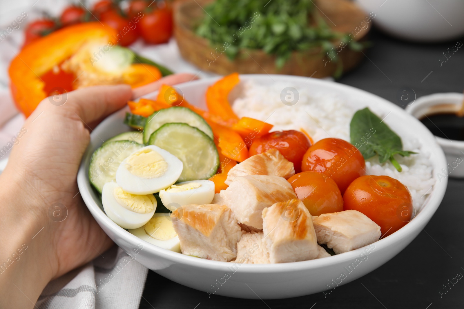 Photo of Woman with delicious poke bowl at black wooden table, closeup