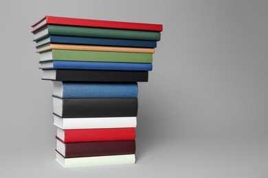 Photo of Stack of different hardcover books on light grey background. Space for text