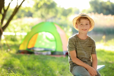 Photo of Little boy near tent outdoors. Summer camp
