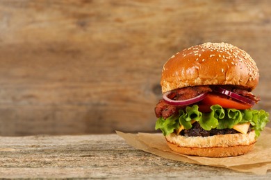 Photo of Tasty burger on wooden table, space for text. Fast food