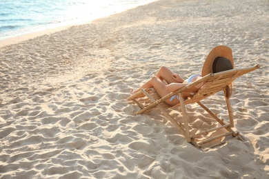 Photo of Young woman relaxing in deck chair on beach