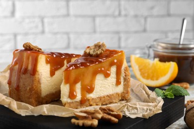 Pieces of delicious caramel cheesecake with walnuts served on table, closeup